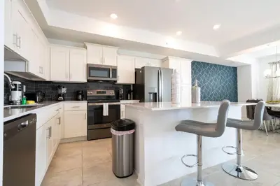 a kitchen with white cabinets and a bar with a stool at 3191 Unit 207 Stunning apartment in Kissimmee