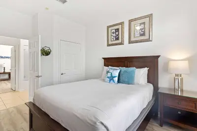 a white bedroom with a large bed with blue pillows at 4814 Cayview Avenue 406 in Orlando