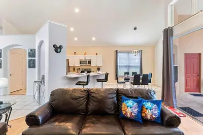 a living room with a leather couch and a dining room at 8213 Fan Palm Way in Kissimmee