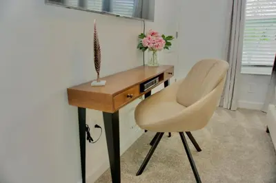a desk with a white chair and a table with flowers at Cozy & Magical place sleeps 12/10 min from Disney in Kissimmee