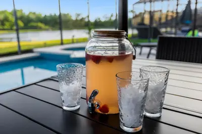 a jar of juice and two glasses on a table at Lake View Vacation Home with Pool and Game Room Near Disney Parks in Kissimmee
