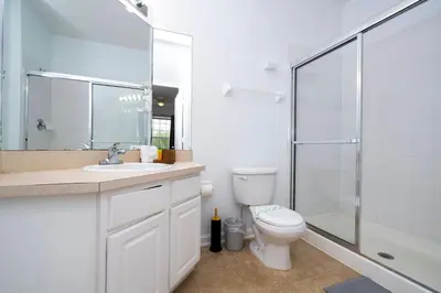 a white bathroom with a toilet and a shower at Dream Cozy 3BR Condo - Disney 5 Min Walk to Pool in Orlando