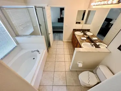 a bathroom with two sinks and a tub and a toilet at Spacious, Open Layout And Pool Relaxation! in Orlando