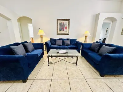 a living room with blue couches and a coffee table at Spacious, Open Layout And Pool Relaxation! in Orlando
