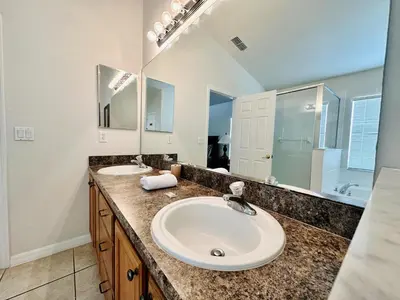 a bathroom with two sinks and a large mirror at Spacious, Open Layout And Pool Relaxation! in Orlando