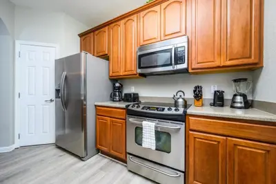 a kitchen with wooden cabinets and stainless steel appliances at Epic Universe Beautiful Condo, Vista Cay, Orlando-3026 in Orlando