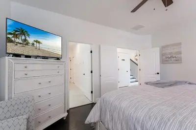 a white bedroom with a bed and a flat screen tv at Lakeview Villa G in Orlando