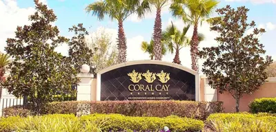 a sign in front of a building with palm trees at 4 bedroom townhouse Sleeps 8 Coral Cay in Kissimmee
