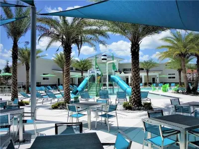 a resort with a slide and tables and palm trees at 6 bedrooms pool home Gated resort Veranda Palms in Kissimmee