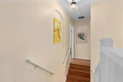 a hallway with a stair railing and paintings on the wall at Lakeview w/8 Bedroom 5 KingSuite 3 miles to Disney in Kissimmee
