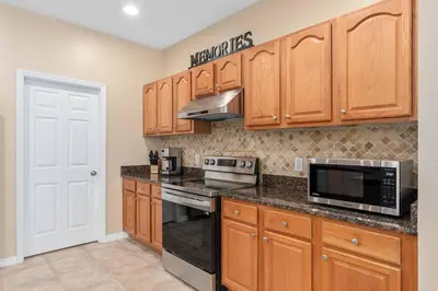 a kitchen with wooden cabinets and a stove top oven at Lakeview w/8 Bedroom 5 KingSuite 3 miles to Disney in Kissimmee