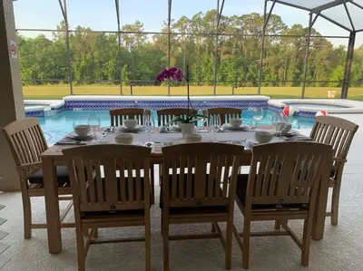 a dining table and chairs with a pool in the background at Lakeview w/8 Bedroom 5 KingSuite 3 miles to Disney in Kissimmee