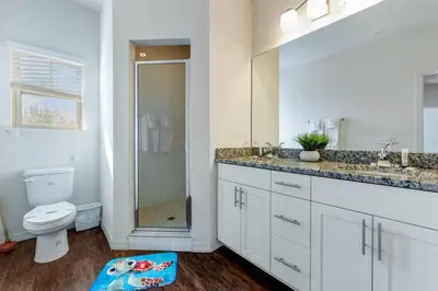 a white bathroom with a toilet and a sink at Disney Dream Resort Amenities Pool *4BD/3BA* Close to Parks in Kissimmee