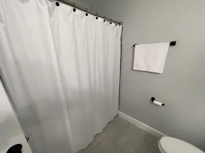 a white shower curtain in a bathroom with a toilet at Family-Friendly DIsney Getaway in Kissimmee