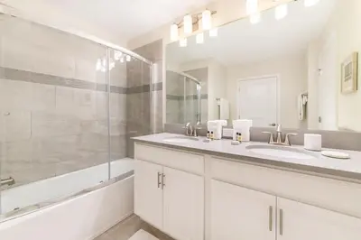 a white bathroom with two sinks and a shower at Magic villa with themed bedrooms and private pool in Kissimmee