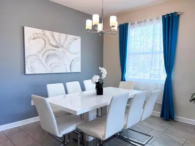 a dining room with a white table and chairs at 5 Bed 5 Bath South Facing Pool Home Storey Lake home in Kissimmee