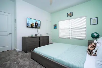 a bedroom with a bed and a television on the wall at Gorgeous 4 Bedroom w Screened Pool Close to Disney 2653 in Kissimmee
