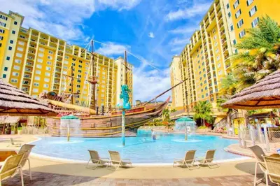 a pool with a pirate ship in the middle of buildings at 2BR Resort Suite - Fountain View Private Balcony in Kissimmee