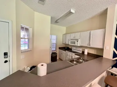 a kitchen with white cabinets and a counter top at Grand Deluxe 3BR Townhouse near Disney Parks in Kissimmee
