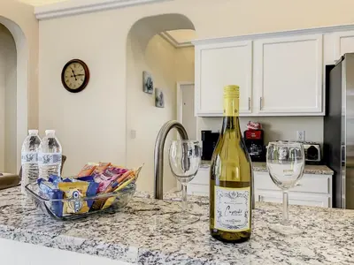 a bottle of wine sitting on a counter with two wine glasses at Family pool home near Disney wBBQ grill in Orlando