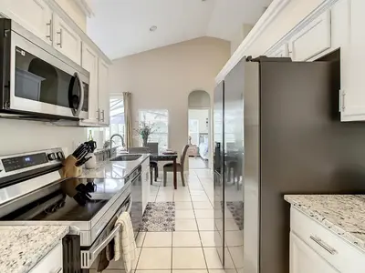 a kitchen with white cabinets and a refrigerator at Family pool home near Disney wBBQ grill in Orlando