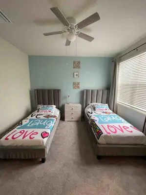 two beds in a room with a ceiling fan at Like home, but better in Orlando