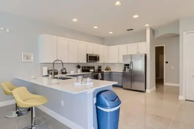 a large kitchen with a counter and a refrigerator at The Marvel Mansion 5BR Pool Home Near Disney World in Orlando