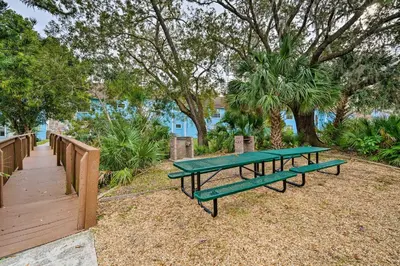 two green picnic tables sitting next to a wooden fence at Kissimmee Vacation Rental - 5 Mi to Disney World! in Kissimmee
