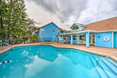 a swimming pool in front of a blue house at Kissimmee Vacation Rental - 5 Mi to Disney World! in Kissimmee