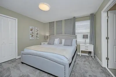 a white bedroom with a large bed and a table at 9 Bedrooms 5 Bathrooms Storey Lake 2854 Bd in Kissimmee