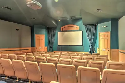 an auditorium with a screen and chairs in front of a podium at Kissimmee Vacation Rental with Pool about 4 Mi to Disney in Kissimmee