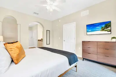 a bedroom with a large white bed and a dresser at 2BR Condo - Pool & Games - Near Disney in Orlando
