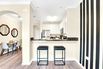 a kitchen and dining room with a counter and stools at 2BR Condo - Pool & Games - Near Disney in Orlando