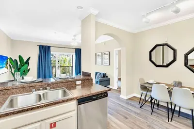 a kitchen with a sink and a table with chairs at 2BR Condo - Pool & Games - Near Disney in Orlando