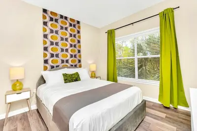 a bedroom with a bed and a window with green curtains at Near Disney - 3BR Condo - Pool and Games in Orlando