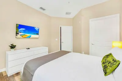 a bedroom with a white bed and a painting on the wall at Near Disney - 3BR Condo - Pool and Games in Orlando