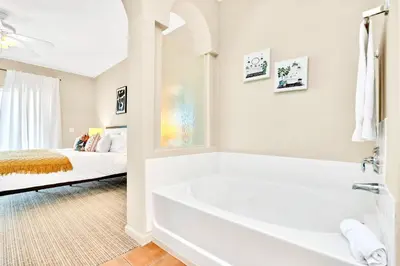a white bathroom with a tub and a bed at 3BR Condo - Pool Sauna - Near Disney in Orlando