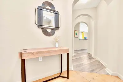 a hallway with a table and a mirror on the wall at 3BR Condo - Pool Sauna - Near Disney in Orlando