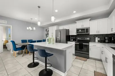 a kitchen with white cabinets and a table and chairs at Magic Condo 3BR at Storey Lake – 10 min to Disney in Kissimmee
