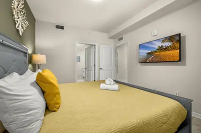 a bedroom with a large bed with a television on the wall at Magic Condo 3BR at Storey Lake – 10 min to Disney in Kissimmee
