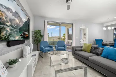 a living room with a couch and blue chairs at Magic Condo 3BR at Storey Lake – 10 min to Disney in Kissimmee