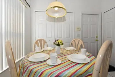 a dining room table with a striped tablecloth and chairs at Rise & Shine! in Orlando