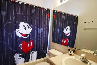 a bathroom with a shower curtain with mickey mouse at Rise & Shine! in Orlando