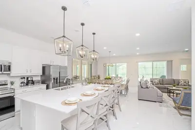 a kitchen and living room with a large white island at Near Disney - 12BR Home - Private Pool and Hot Tub in Kissimmee