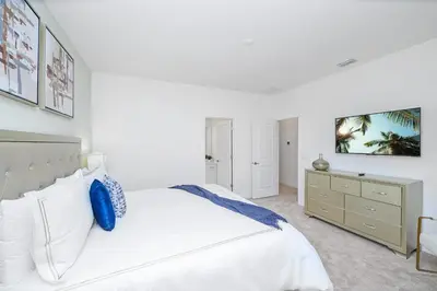 a white bedroom with a bed and a dresser at Near Disney - 12BR Home - Private Pool and Hot Tub in Kissimmee