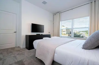 a white bedroom with a bed and a television at Brand new fantastic home at Storey lake (SL4447) in Kissimmee