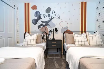 a bedroom with two beds and a cartoon mouse on the wall at Brand new fantastic home at Storey lake (SL4447) in Kissimmee