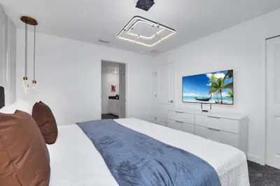 a white bedroom with a bed and a tv at Perfect Disney Vacation Home in Kissimmee