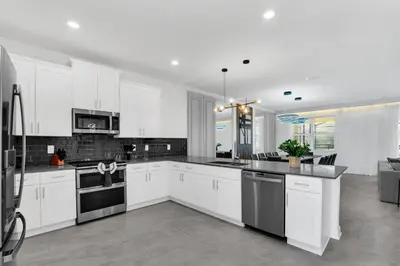 a kitchen with white cabinets and black appliances at Perfect Disney Vacation Home in Kissimmee