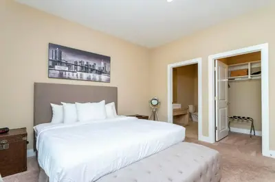 a bedroom with a large white bed with a ottoman at Modern and Luxury 4 suites close to Disney 7544 in Orlando